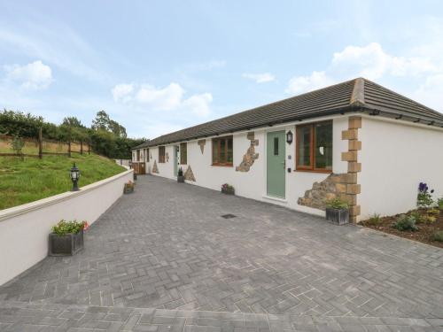 a small white building with a driveway at Bumble Bee Retreat in Axminster
