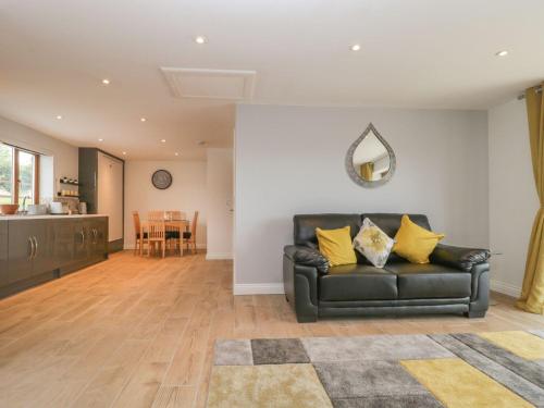a living room with a black leather couch and a table at Bumble Bee Retreat in Axminster