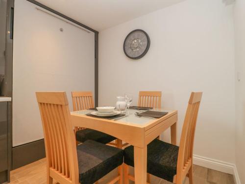 a dining room table with chairs and a clock on the wall at Bumble Bee Retreat in Axminster