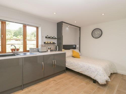 a bedroom with a bed and a sink and a clock at Bumble Bee Retreat in Axminster