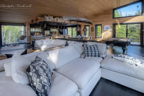 a living room with a white couch and a piano at Chalet TIPI, Chic Charme & Nature in La Malbaie