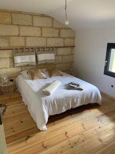 Cette chambre comprend un grand lit blanc et un mur en briques. dans l'établissement GITE Killiam et Madison, à Saint-Denis-de-Pile