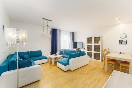 una sala de estar con sofás azules y una mesa. en Golden Dune 100m od plaży, en Międzyzdroje