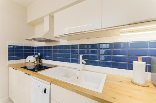 cocina con fregadero y pared de azulejos azules en Golden Dune 100m od plaży, en Międzyzdroje