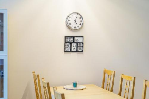 a dining room table with chairs and a clock on the wall at Golden Dune 100m od plaży in Międzyzdroje