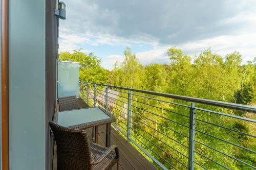 a balcony with two chairs and a table and a view of trees at Golden Dune 100m od plaży in Międzyzdroje