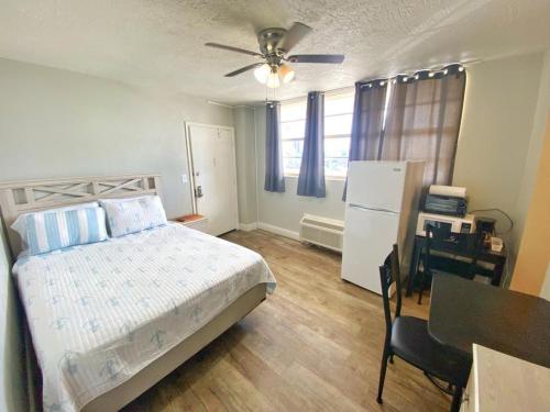 a bedroom with a bed and a table and a refrigerator at Sea Dip Resort Studios! in Daytona Beach