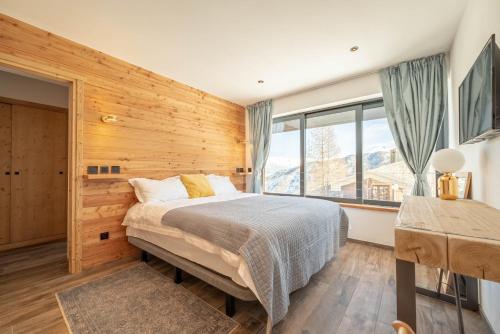 una camera da letto con un letto e una grande finestra di Chalet Lumière - LaGodille Prestige - 16 personnes - Pra Loup a Uvernet