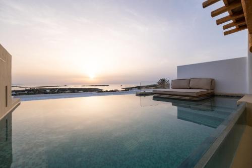 a villa with a swimming pool with a couch on top of it at Anna Platanou Suites in Agia Irini Paros