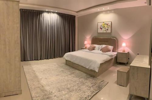 een slaapkamer met een bed met 2 lampen en een tapijt bij شقق العارض in Riyad