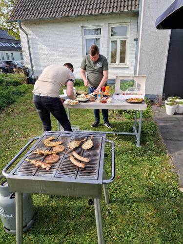 two men cooking sausages on a grill at De Slaapfabriek vakantiehuis en trainingslocatie in Teuge