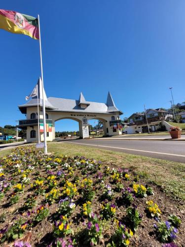 a flag flying in front of a building with flowers at Pousada do Pórtico in Gramado