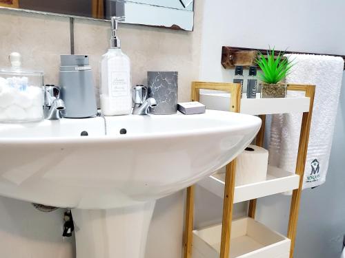 La salle de bains est pourvue d'un lavabo blanc et d'une étagère. dans l'établissement Mnqobi Lifestyle Apartments, à Nelspruit
