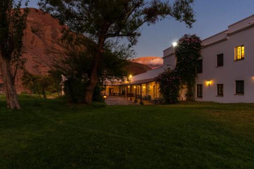 a house with a tree in the yard at night at Hotel El Manantial del Silencio in Purmamarca