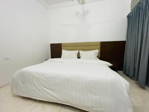 a bedroom with a large bed with white sheets at Al Rakaez Tourist Hostel in Al Hada