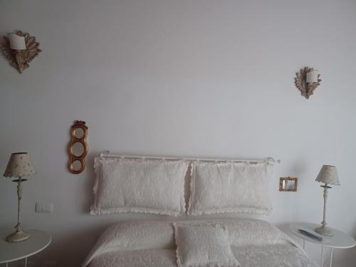 um quarto branco com uma cama com lençóis e almofadas brancos em CASA RE.ALE em Viterbo