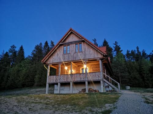 eine große Blockhütte mit eingeschaltetem Licht in einem Wald in der Unterkunft Osada na Granicy - Domki w Bieszczadach in Ustrzyki Dolne