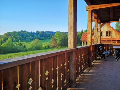 un portico di un edificio in legno con sedie sopra di Osada na Granicy - Domki w Bieszczadach a Ustrzyki Dolne