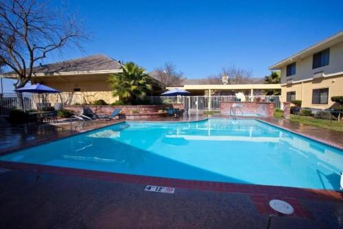a large blue swimming pool in front of a building at La Casa Modesto, Ascend Hotel Collection in Modesto