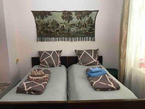 a bedroom with two beds with pillows and a painting on the wall at Lada Guest House in Tbilisi City