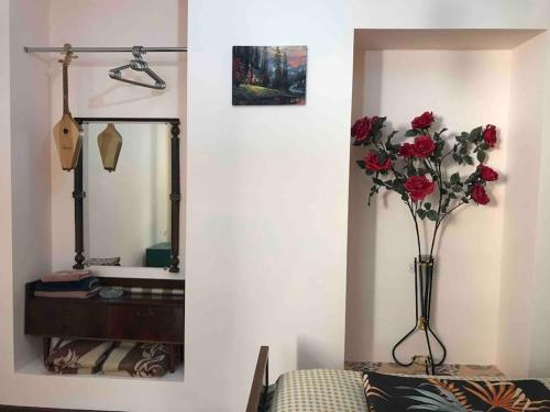 a vase of roses in a room with a mirror at Lada Guest House in Tbilisi City