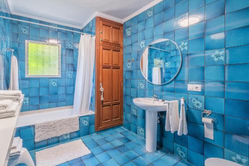Baño de azulejos azules con lavabo y espejo en Villa Son Bibiloni, en Algaida