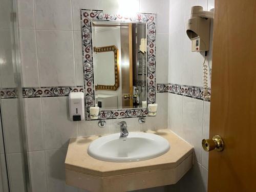 a bathroom with a sink and a mirror at Real Caparica Hotel in Costa da Caparica