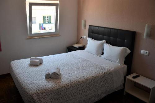 een slaapkamer met een bed met twee slippers erop bij Alojamentos Vitinho - Vila Nova Milfontes in Vila Nova de Milfontes