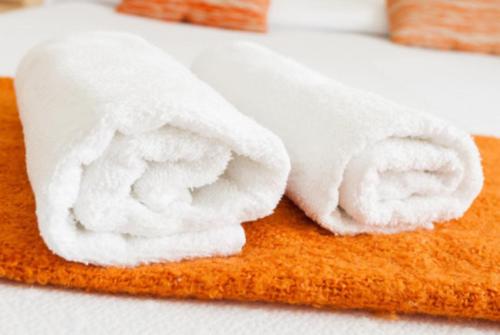 a roll of white towels sitting on top of a bed at BcnStop Parc Güell in Barcelona
