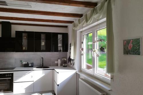 una cocina con armarios blancos y una ventana en Ferienwohnung Schmidt, en Airlenbach