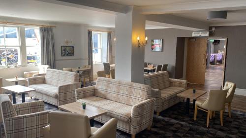 a waiting room with couches and tables and chairs at Caledonian Hotel 'A Bespoke Hotel’ in Ullapool