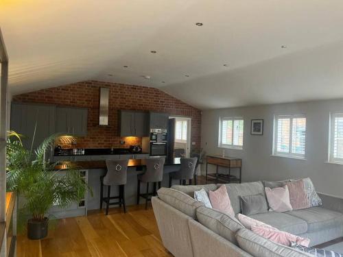 a living room with a couch and a kitchen at 2 Bedroom Barn Conversion in Leicester