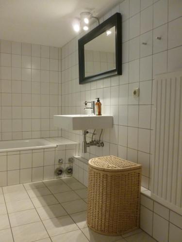 La salle de bains est pourvue de carrelage blanc, d'un lavabo et d'une baignoire. dans l'établissement Strandnahe Ostsee Ferienwohnung in Schönberg, 90m², mit Terrasse, à Schönberg in Holstein