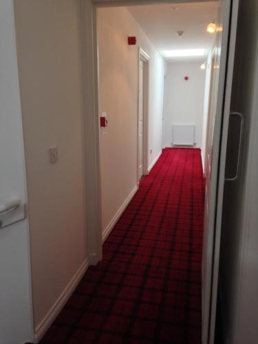 an empty corridor with a red carpet in a hallway at Rosebank Guest House in Perth