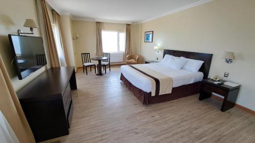 a hotel room with a bed and a flat screen tv at Hotel Diego De Almagro Arica in Arica