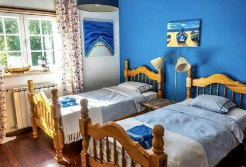 Duas camas num quarto com paredes azuis em Fantastic house swimmingpool jacuzzi horses em Alcobaça