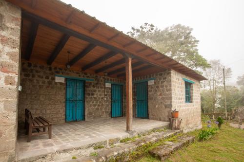 a stone house with blue doors and a wooden roof at Niebli Historical Farm and Lodge at Pululahua Volcano in Quito