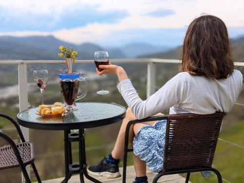 a woman sitting at a table with a glass of wine at 4 seasons. 4 სეზონი Glamping Georgia Racha in Ambrolauri