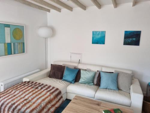 uma sala de estar com um sofá branco e almofadas azuis em The Coach House- Stunning Detached Coastal home, with parking, by Historic Deal Castle em Deal