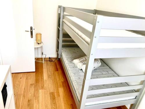 Ce lit superposé blanc se trouve dans un dortoir doté de parquet. dans l'établissement Deux pièces familial chic et confortable - Square Courteline - Nation - Paris centre, à Paris