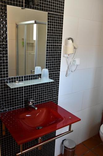 a bathroom with a red sink and a mirror at Alojamentos Vitinho - Vila Nova Milfontes in Vila Nova de Milfontes