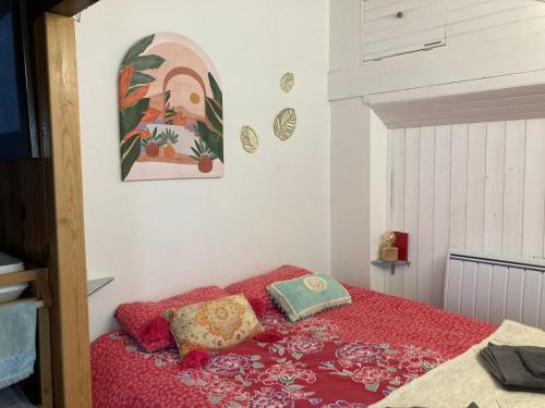 Schlafzimmer mit einem Bett mit einer roten Tagesdecke in der Unterkunft Le Petit Ecrin, 80 m de la mer in Le Pouliguen