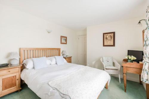 a bedroom with a large white bed and a chair at Highfield Lodge in Tring