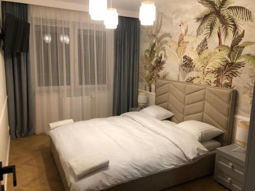 ein Schlafzimmer mit einem großen weißen Bett mit einer tropischen Tapete in der Unterkunft Solankowa Aleja Apartament Egzotyczny in Inowrocław