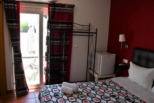 a bedroom with a bed and a door to a patio at Alojamentos Vitinho - Vila Nova Milfontes in Vila Nova de Milfontes