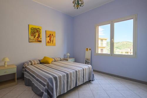 a white bedroom with a bed and a window at Corbezzolo in Bari Sardo