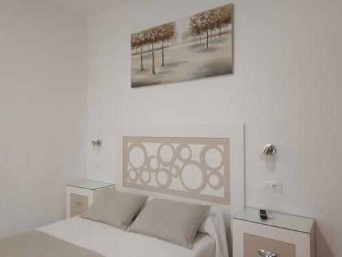 Hostal Los Arcos في تشايبيونا: غرفة نوم بيضاء مع سرير وطاولتين