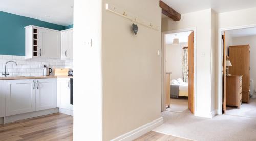 a kitchen with white cabinets and a room with a bed at Bassicks at the Graythwaite Estate in Ulverston