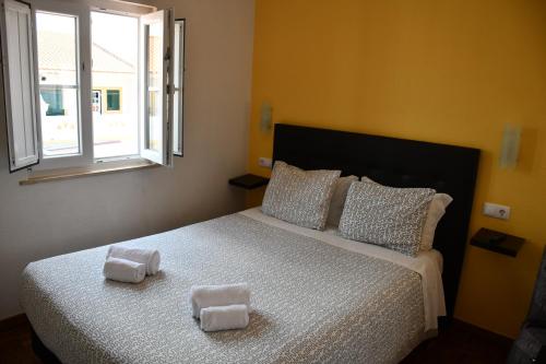 a bedroom with a bed with two towels on it at Alojamentos Vitinho - Vila Nova Milfontes in Vila Nova de Milfontes