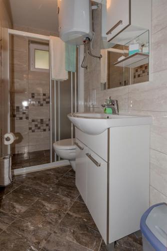 a white bathroom with a sink and a toilet at Apartman Domenika in Makarska